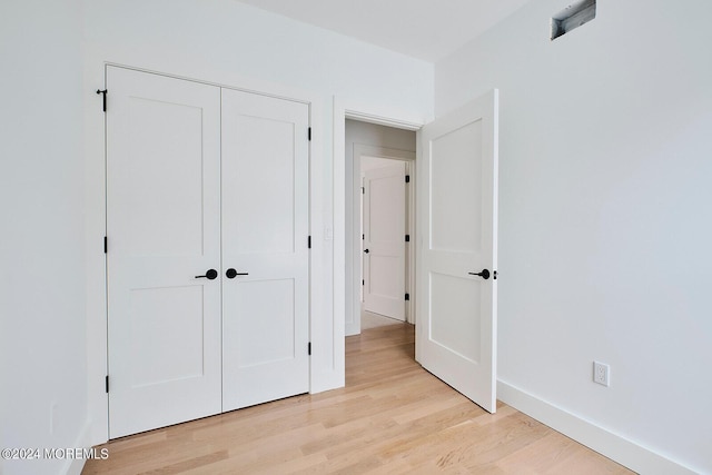 unfurnished bedroom with light wood-type flooring and a closet