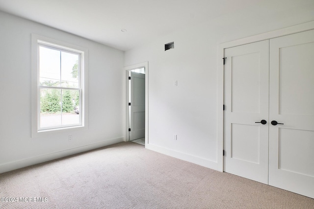 unfurnished bedroom featuring light colored carpet and a closet