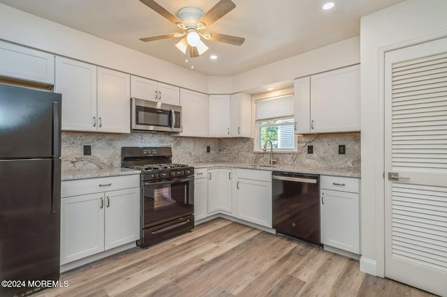 kitchen with white cabinetry, sink, decorative backsplash, black appliances, and light wood-type flooring