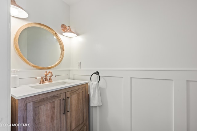 bathroom featuring a wainscoted wall, vanity, and a decorative wall