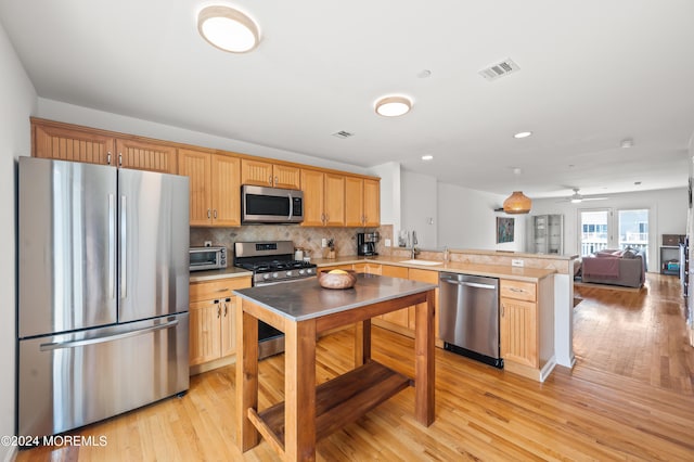 kitchen featuring tasteful backsplash, visible vents, light wood-style flooring, appliances with stainless steel finishes, and a peninsula