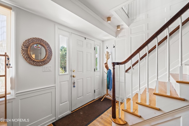 foyer entrance with wood finished floors, stairs, and a decorative wall