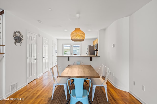 dining space featuring visible vents, light wood-style flooring, and baseboards