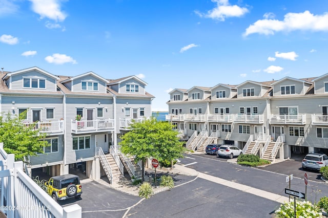 view of building exterior with stairway, a residential view, and uncovered parking