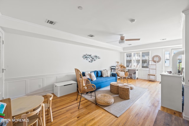 living room with ceiling fan, visible vents, light wood finished floors, and wainscoting