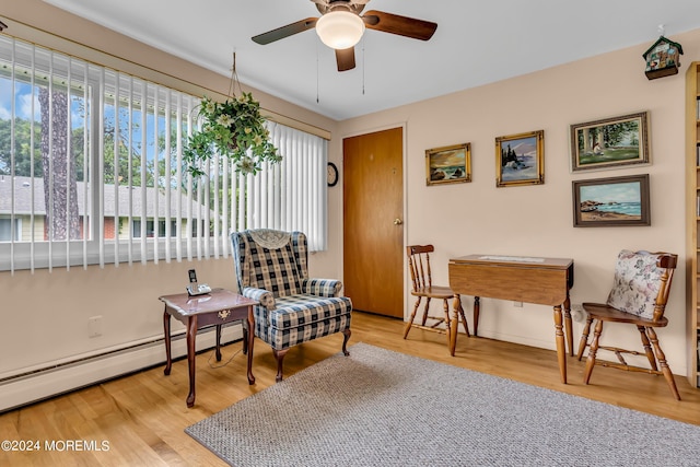 living area with light wood-type flooring, baseboard heating, and ceiling fan