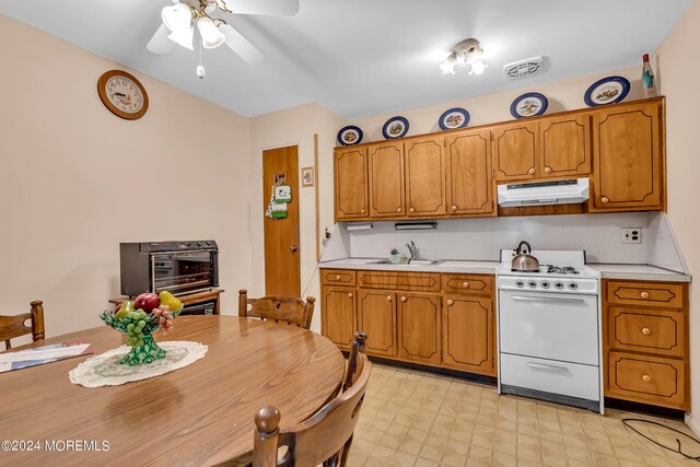 kitchen featuring light tile patterned floors, sink, white gas range, and ceiling fan