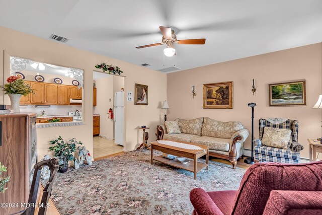 tiled living room featuring a baseboard heating unit, sink, and ceiling fan