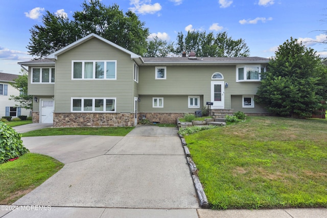 raised ranch featuring a garage and a front yard