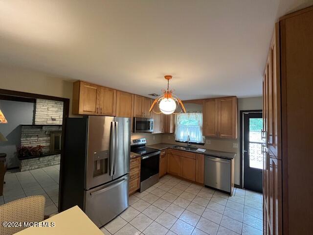 kitchen with sink, stainless steel appliances, light tile patterned floors, and hanging light fixtures