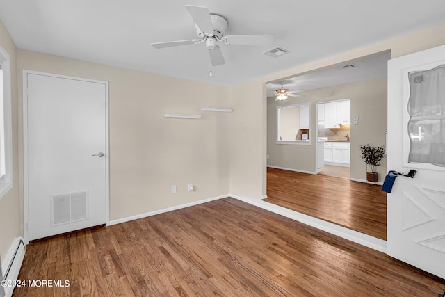 unfurnished room featuring a baseboard radiator, ceiling fan, and hardwood / wood-style floors