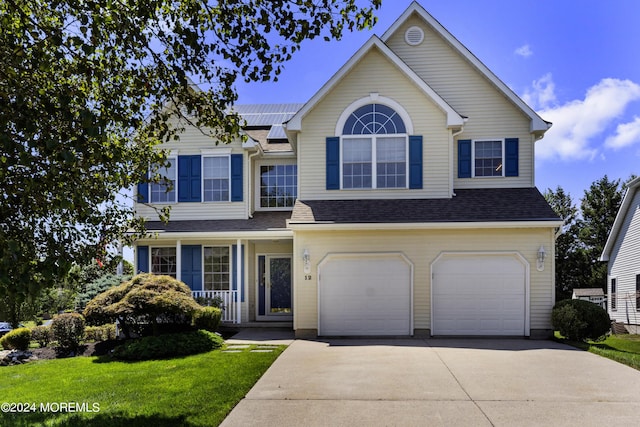 view of front of home with a garage, a front lawn, and solar panels