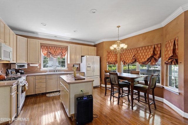 kitchen with white appliances, light hardwood / wood-style floors, sink, a kitchen island, and pendant lighting