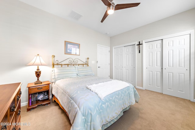 bedroom featuring multiple closets, ceiling fan, and light colored carpet