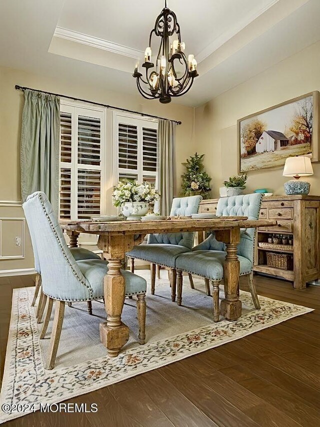 dining room featuring a chandelier, a raised ceiling, ornamental molding, and dark hardwood / wood-style floors