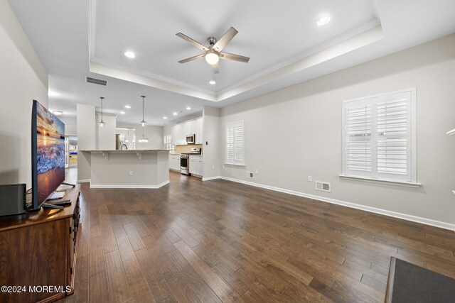 living room with ceiling fan, a tray ceiling, dark hardwood / wood-style floors, and crown molding