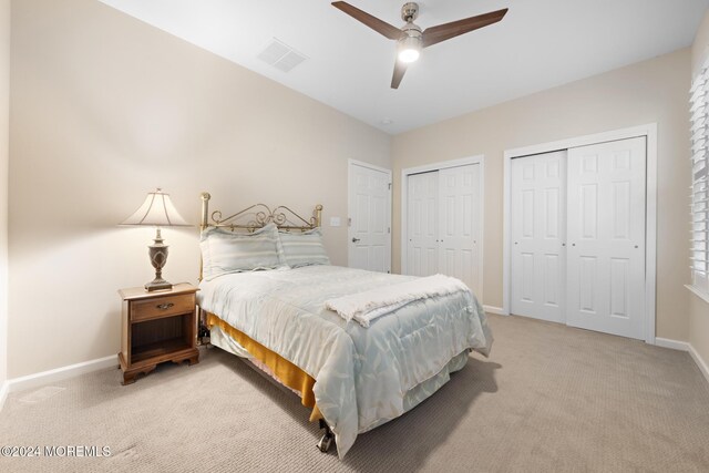 carpeted bedroom with multiple closets and ceiling fan