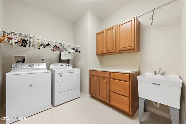 laundry room with sink, washer and clothes dryer, and cabinets