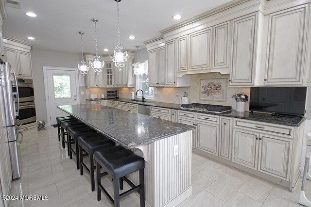 kitchen featuring light tile patterned floors, dark stone counters, a kitchen island, stainless steel appliances, and decorative backsplash