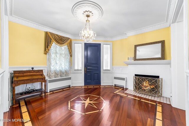 interior space with radiator heating unit, ornamental molding, a notable chandelier, and hardwood / wood-style floors