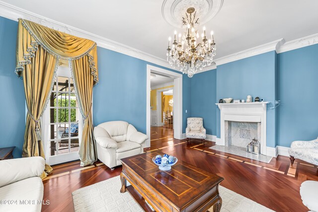 living room featuring a fireplace, crown molding, wood-type flooring, and a notable chandelier