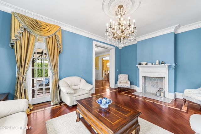 living room featuring ornamental molding, wood-type flooring, a fireplace, and a notable chandelier