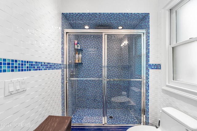 bathroom with an enclosed shower, tile walls, and toilet