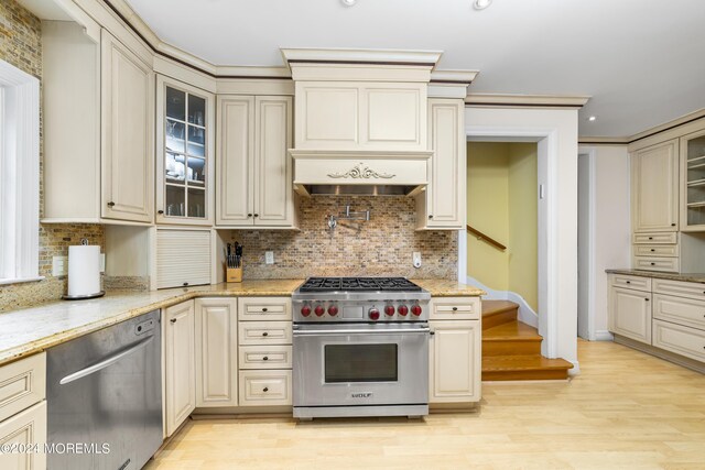 kitchen with appliances with stainless steel finishes, light hardwood / wood-style flooring, decorative backsplash, and light stone countertops