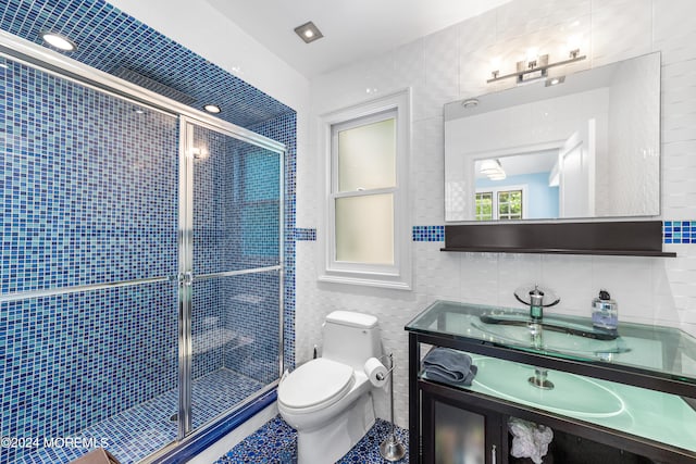 bathroom with a shower with shower door, tile walls, backsplash, toilet, and vanity