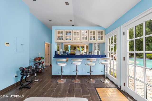 bar with high vaulted ceiling, electric panel, and dark hardwood / wood-style floors