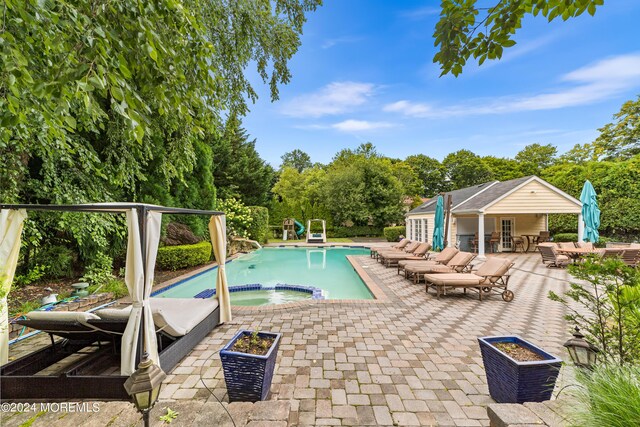 view of swimming pool featuring an in ground hot tub and a patio area