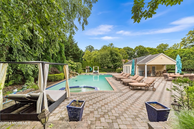 view of swimming pool with an outbuilding, an outdoor bar, an in ground hot tub, and a patio area