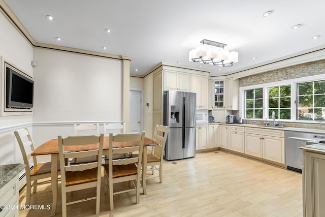 kitchen with pendant lighting, stainless steel appliances, crown molding, and cream cabinetry