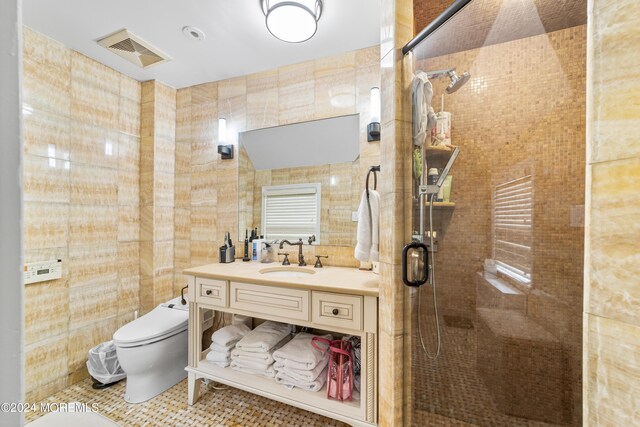 bathroom featuring vanity, tile patterned floors, tile walls, a shower with shower door, and toilet