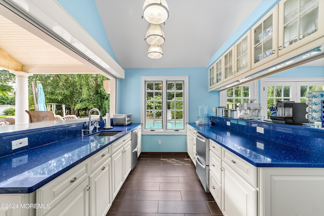 kitchen with white cabinetry, sink, vaulted ceiling, and dark stone countertops