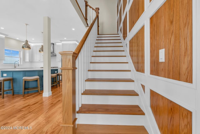 stairway featuring sink and light wood-type flooring