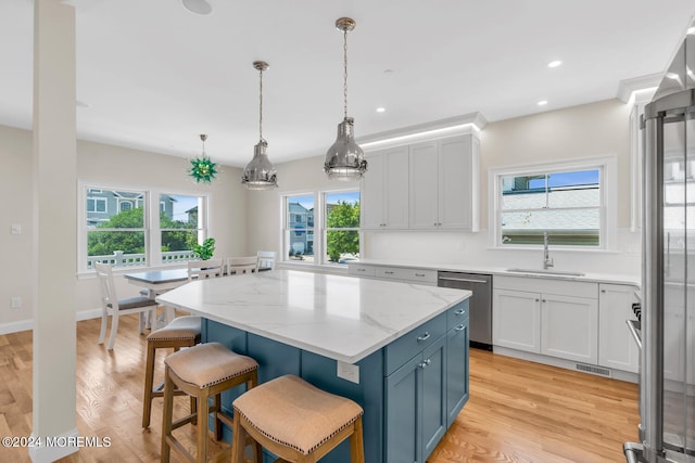 kitchen with stainless steel dishwasher, white cabinets, pendant lighting, light wood-type flooring, and sink