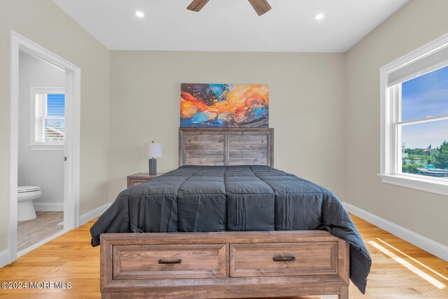 bedroom with light hardwood / wood-style floors, multiple windows, connected bathroom, and ceiling fan