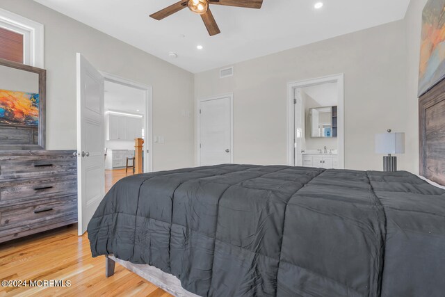 bedroom featuring light hardwood / wood-style flooring, ensuite bathroom, and ceiling fan