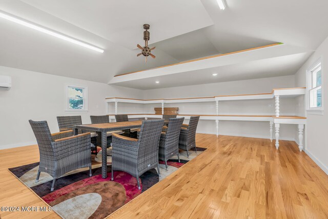 dining room with a wall unit AC, ceiling fan, light hardwood / wood-style flooring, and vaulted ceiling