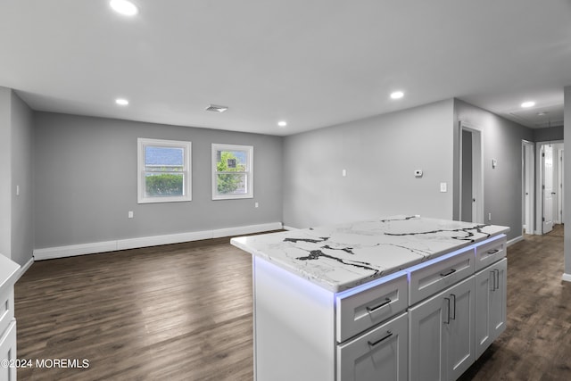 kitchen featuring dark hardwood / wood-style floors, light stone countertops, and a kitchen island