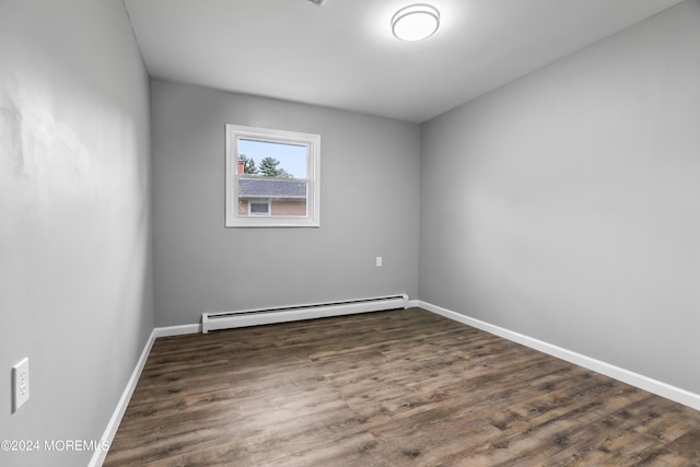 empty room featuring baseboard heating and dark hardwood / wood-style floors