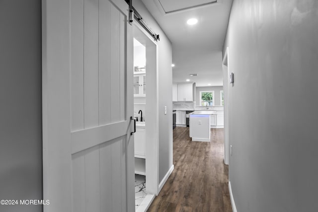 corridor with dark hardwood / wood-style flooring and a barn door