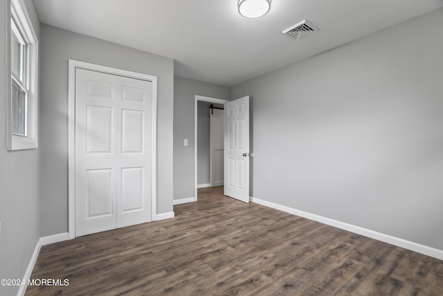 unfurnished bedroom featuring dark wood-type flooring and a closet