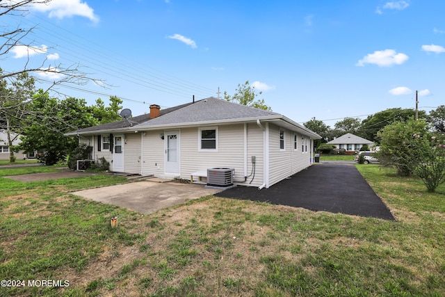 rear view of property featuring central AC unit, a patio area, and a yard