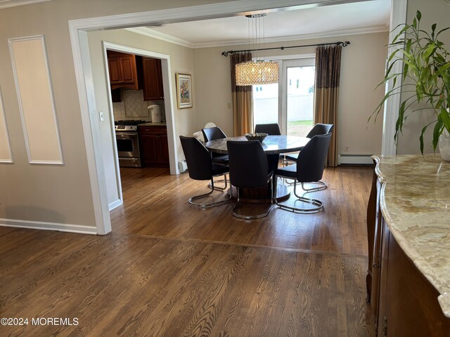 dining room featuring dark hardwood / wood-style floors, crown molding, a baseboard heating unit, and an inviting chandelier