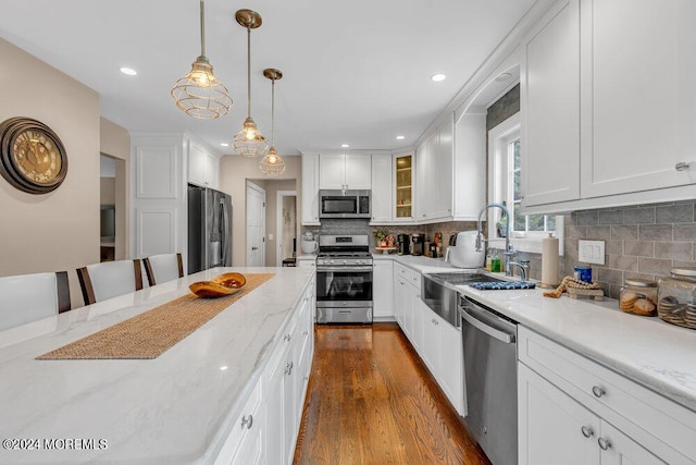 kitchen with hanging light fixtures, white cabinetry, appliances with stainless steel finishes, and sink