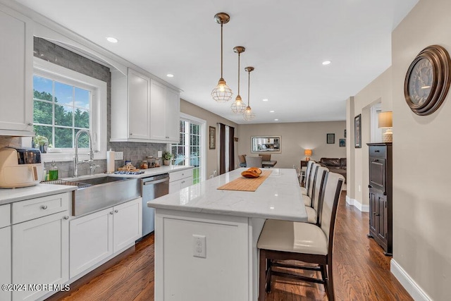 kitchen featuring white cabinetry, dishwasher, a kitchen island, and decorative light fixtures