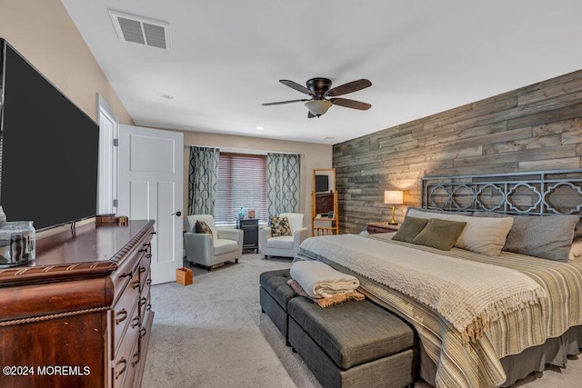 bedroom featuring ceiling fan, light carpet, and wood walls