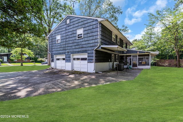 view of side of property with a garage, cooling unit, a lawn, and aphalt driveway